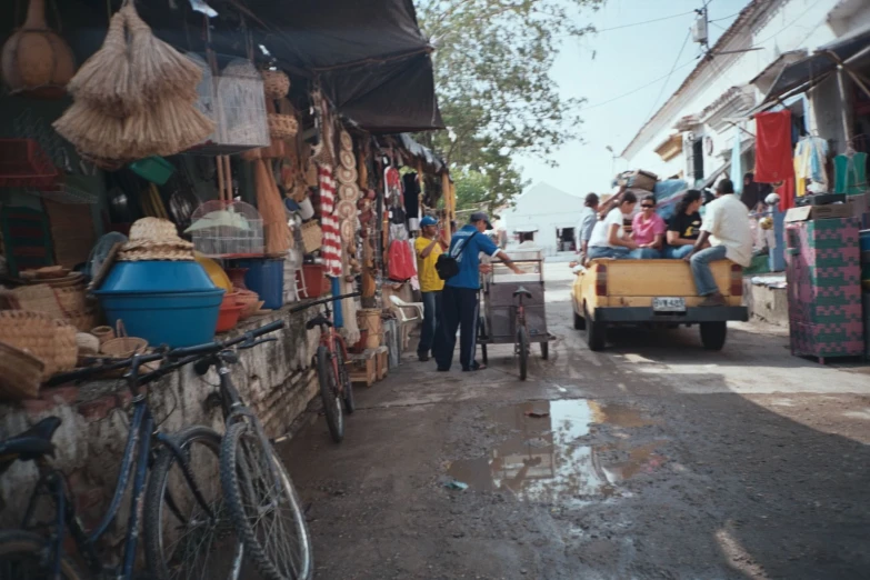 the people are standing near several store's and parked bicycles