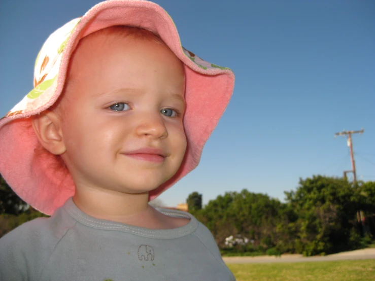 a little girl wearing a pink hat smiling at the camera