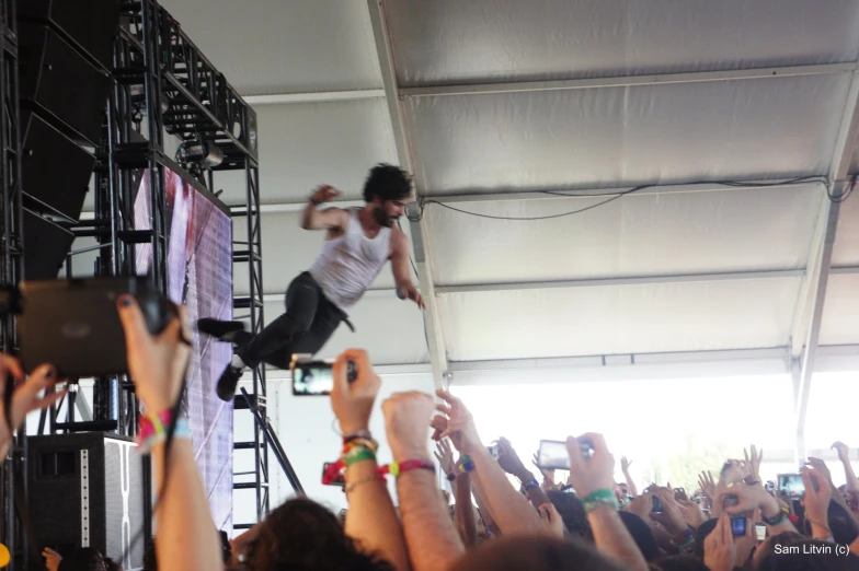 the man is jumping above the crowd on the stage