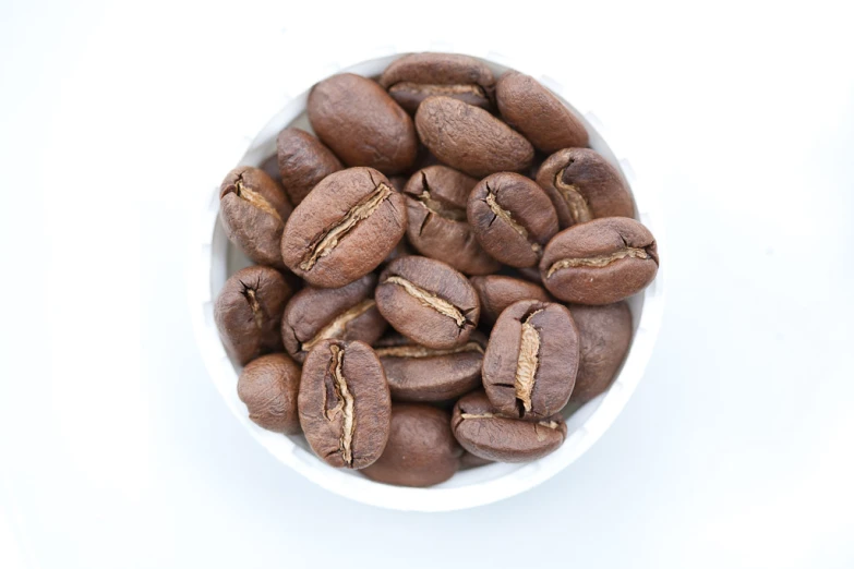 a cup full of coffee beans on top of a white table