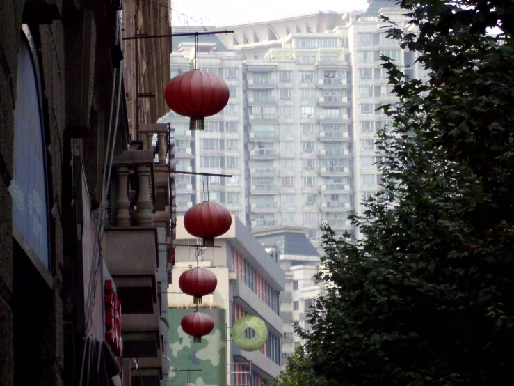 some red lanterns hanging from the side of buildings in a city