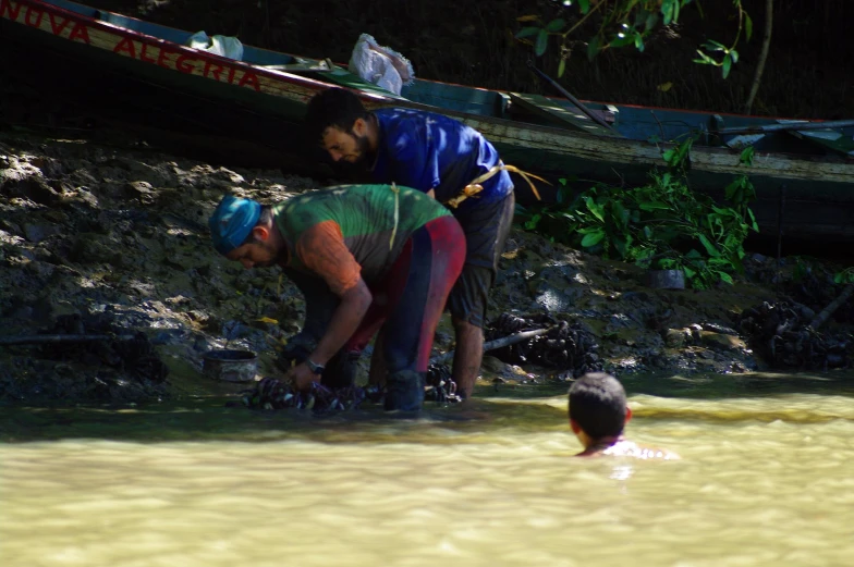 three men near the shoreline trying to wade