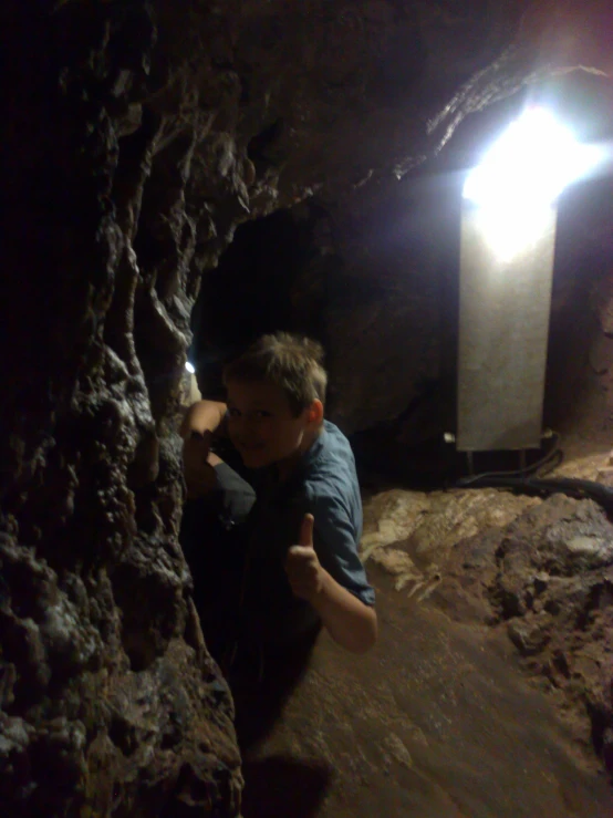 a man sitting on the rocks in a cave pointing at soing