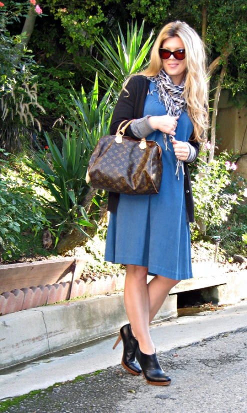 a woman wearing sunglasses holding a brown purse