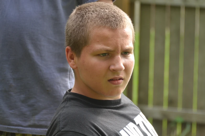 a man in a black shirt standing behind a fence