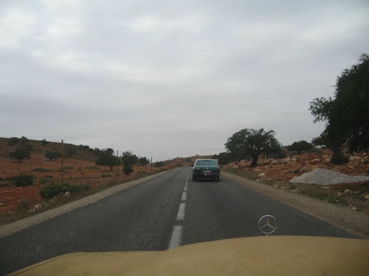 a vehicle driving on a road near some trees