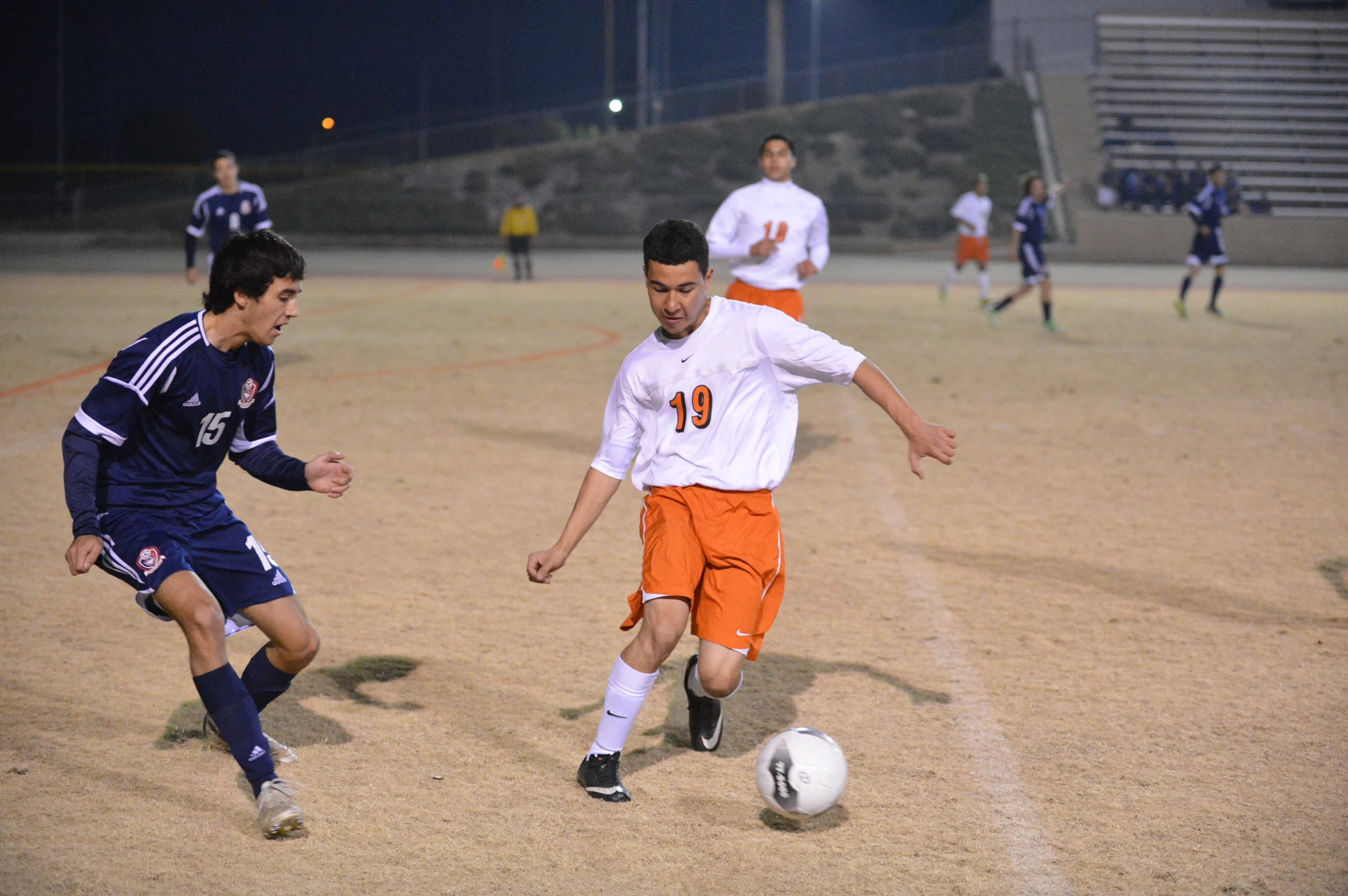 a boy wearing an orange uniform and other boys playing soccer