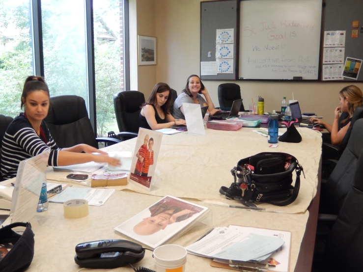 a group of women sitting at a table with papers and laptops