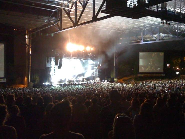 a crowd is watching a concert with a wide screen on stage