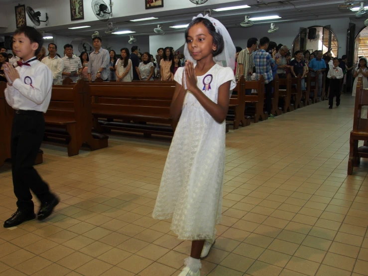 children are in church with their hands up to pray