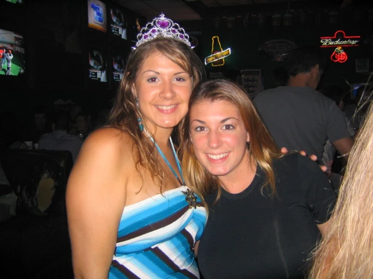 two women pose for the camera in front of a bar