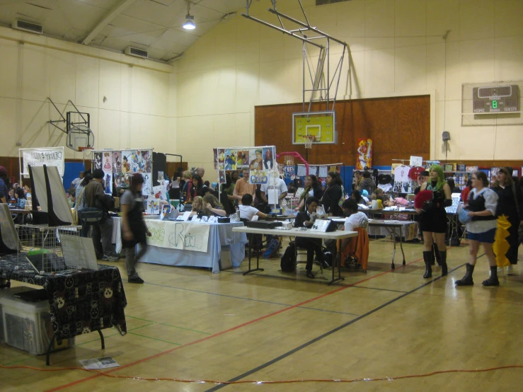 people at tables in a gymnasium for a community event