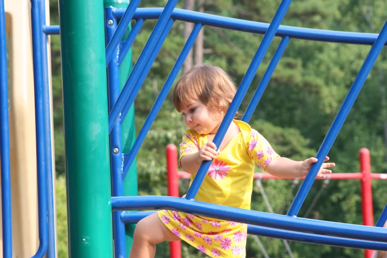 a baby in yellow playing on a slide