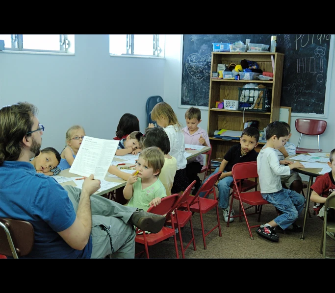 a classroom with lots of children and adults sitting at desk