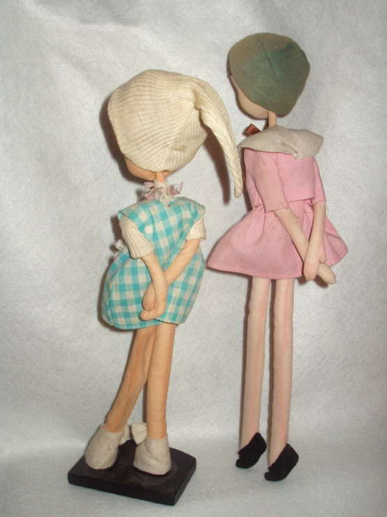 two dolls standing next to each other wearing hats