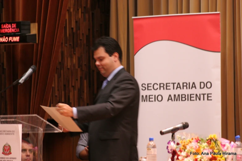 man in black suit standing behind the podium giving a speech