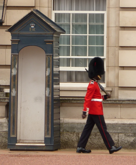 a guard in a uniform walking past a building