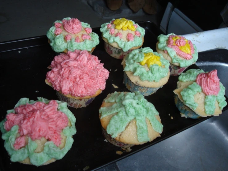 a tray of cupcakes decorated with colorful frosting