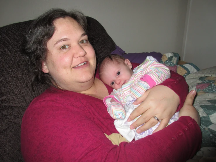 a woman holds a baby wrapped in a blanket