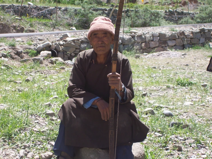 an old woman sitting on rocks holding an umbrella