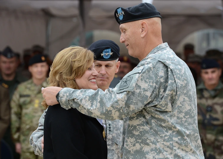 soldier saluting lady in uniform as other military personnel look on