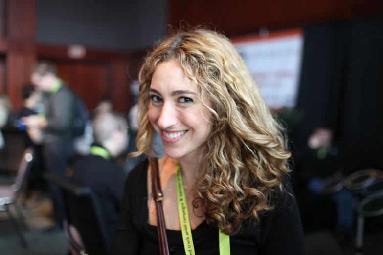 a woman smiling for the camera and showing off her nametag