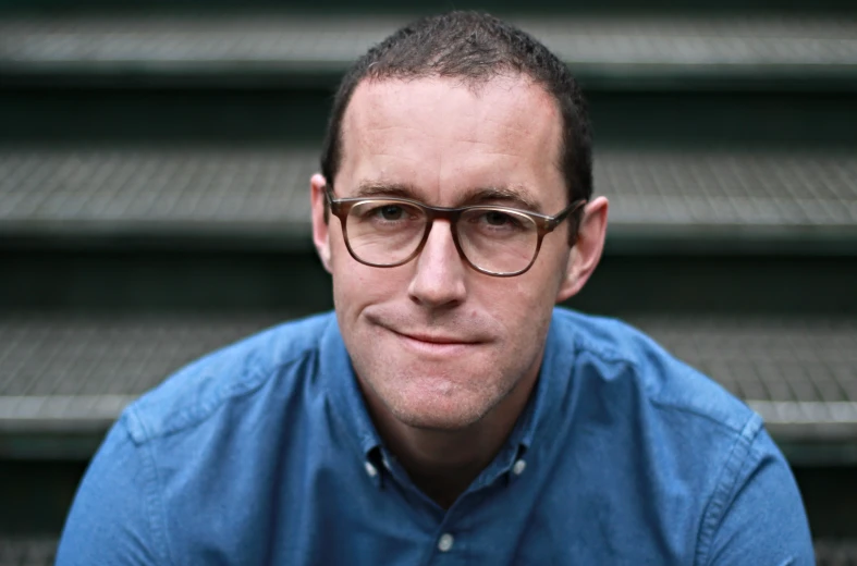 a man in glasses sitting on the steps of some stairs