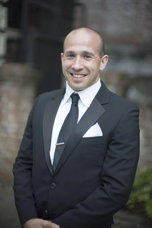 a smiling man in a tuxedo and a black tie