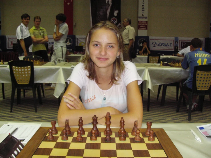 a lady sitting at a table with chess pieces