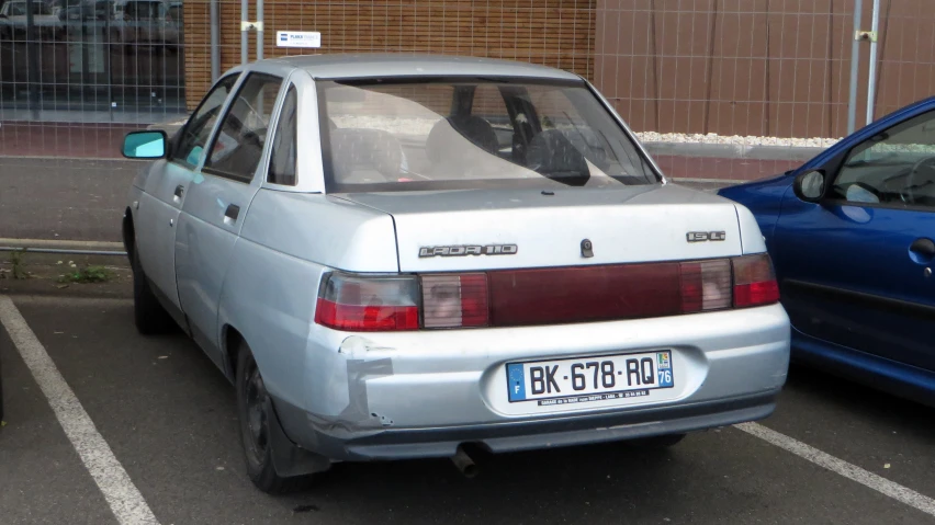 a silver car is parked in a parking space with a blue car