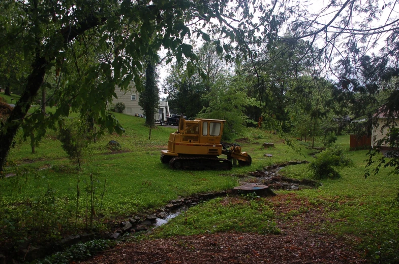 a yellow bulldozer driving along through a green field