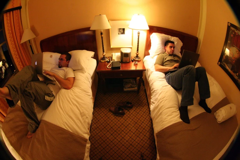 two men laying in bed in a mirror