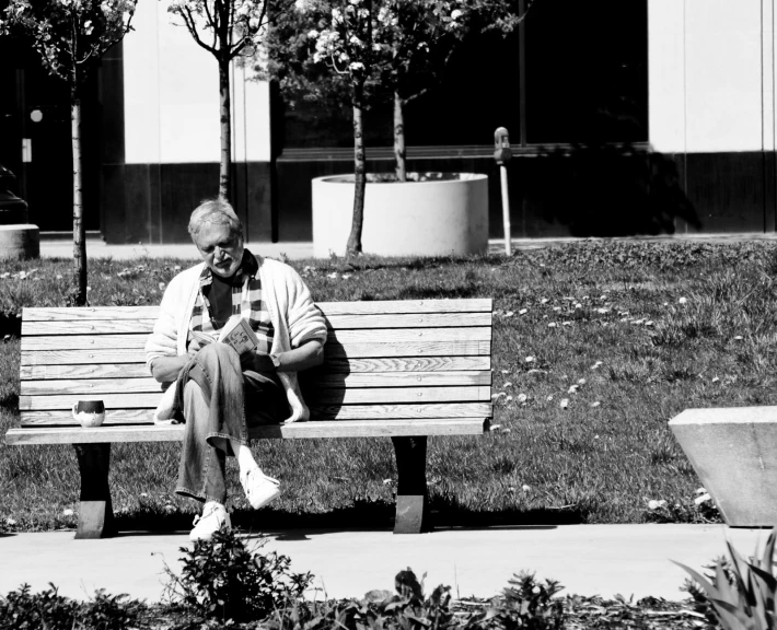 a man sitting on a park bench in the shade