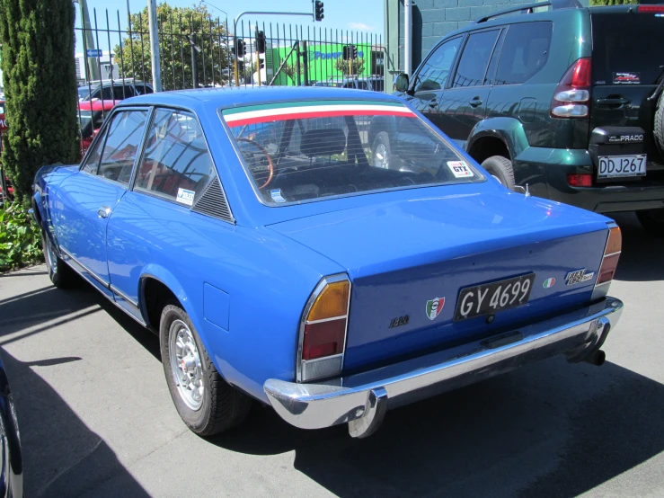 an old blue car parked in the parking lot