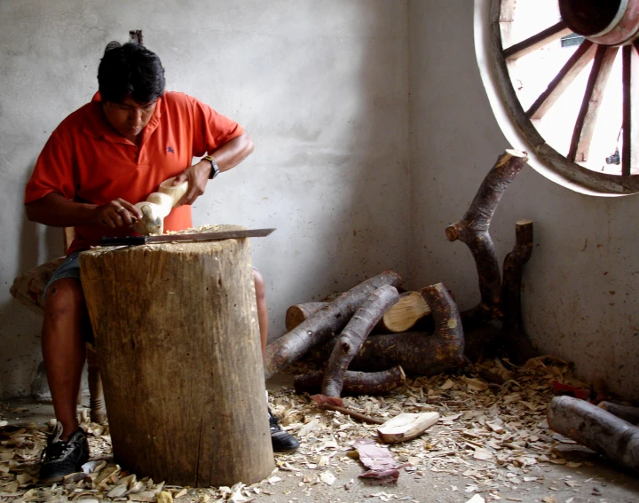 a man working on some wood using his mitt
