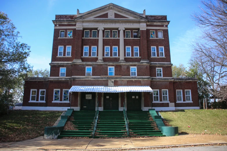 large brick building with steps and green benches