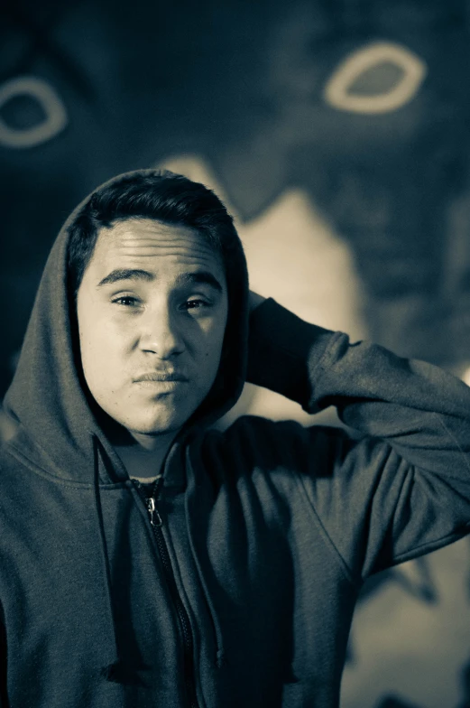 a young man wearing a hooded jacket and hoodie looking at the camera