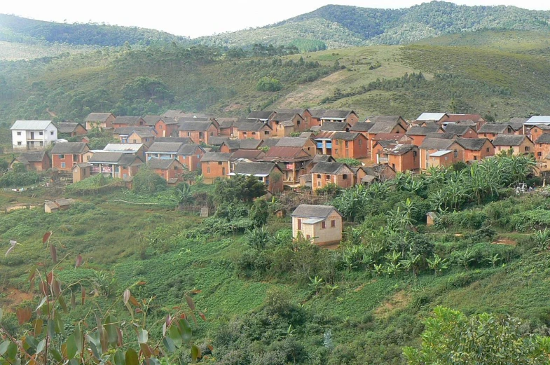 a group of houses on a hill with mountains in the background