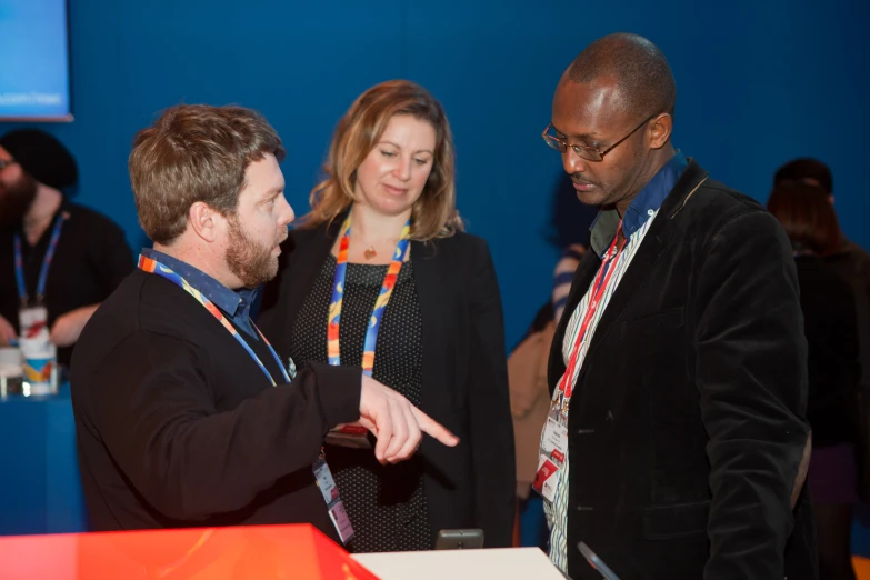 a man speaking to two people in a room