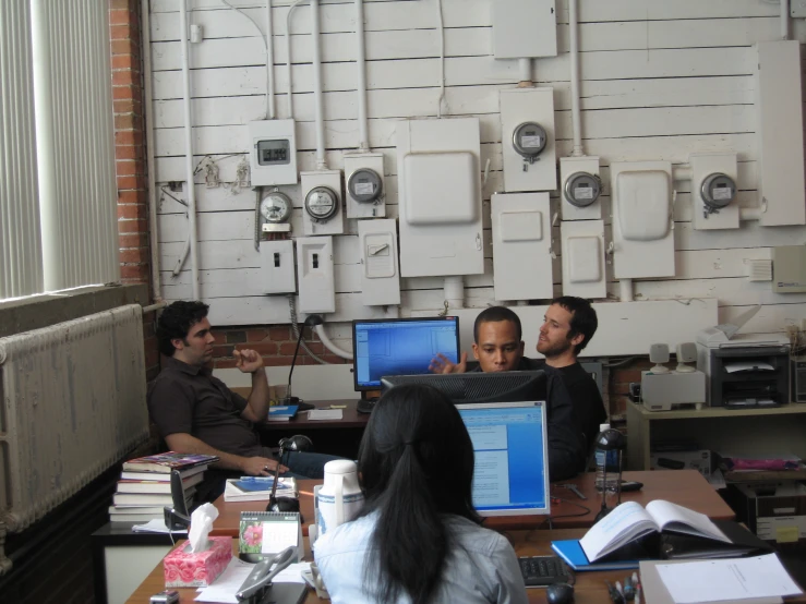 a room full of men and women working on laptops