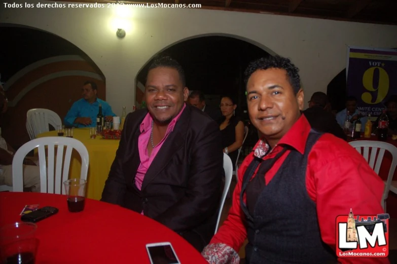 two men sitting at a table in a restaurant, smiling