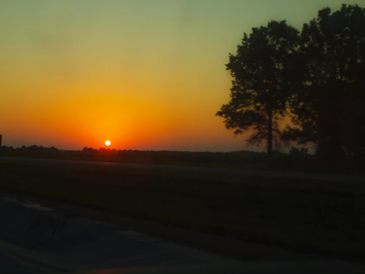 a view of a sunset with cars driving on it