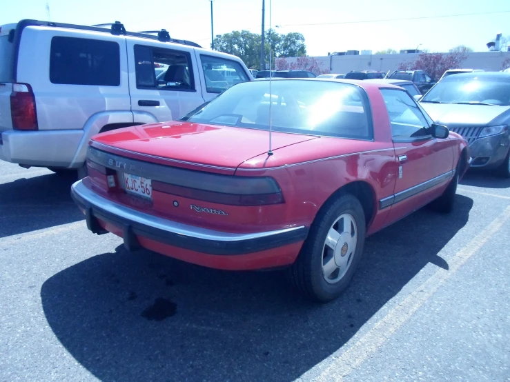 a red car parked in a parking lot with other cars nearby