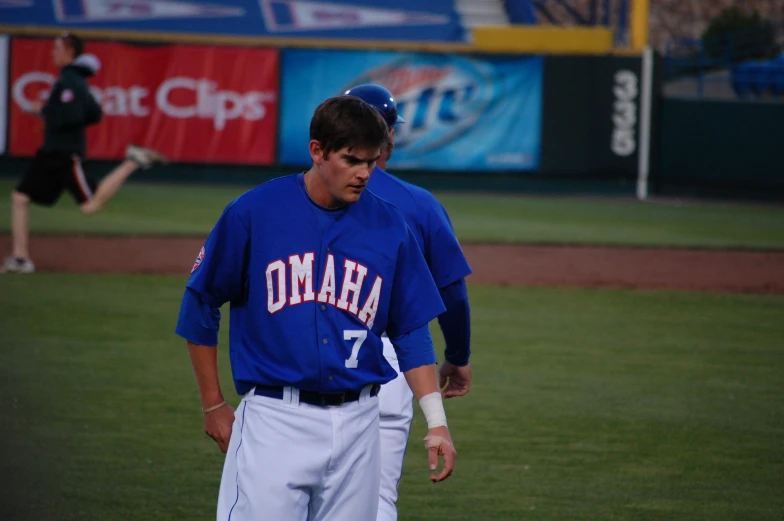 baseball player with elbow in the air walking across field