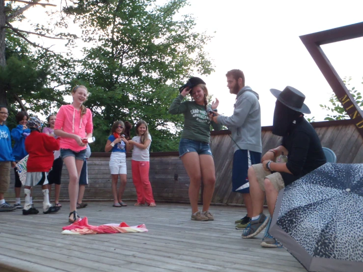 the group of people are standing around on the wooden deck