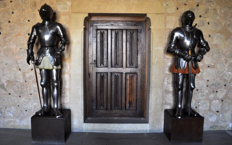 two statues stand near a wood door