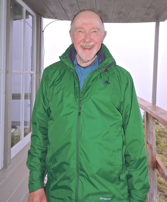 man with beard and a green coat smiling at the camera