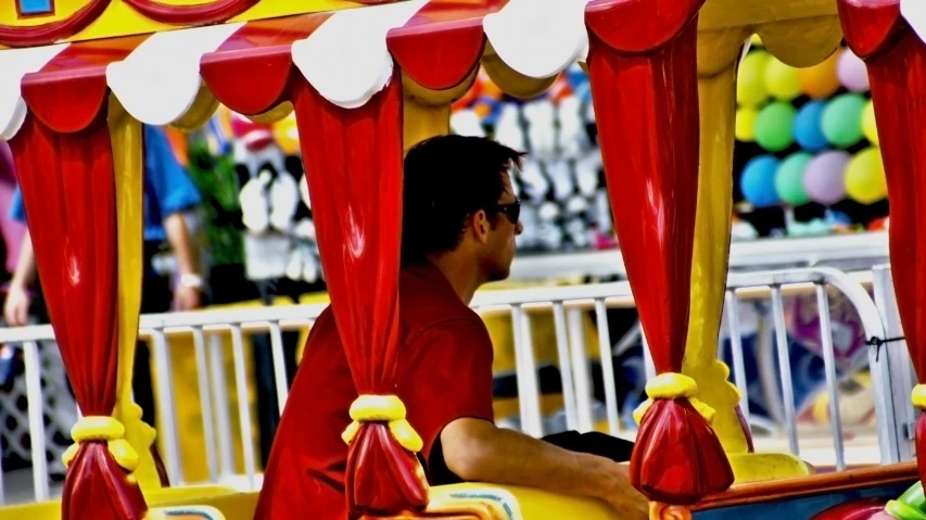 a  riding a toy train with lots of balloons in the background