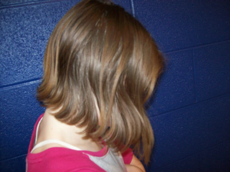 a young child is standing by a blue wall