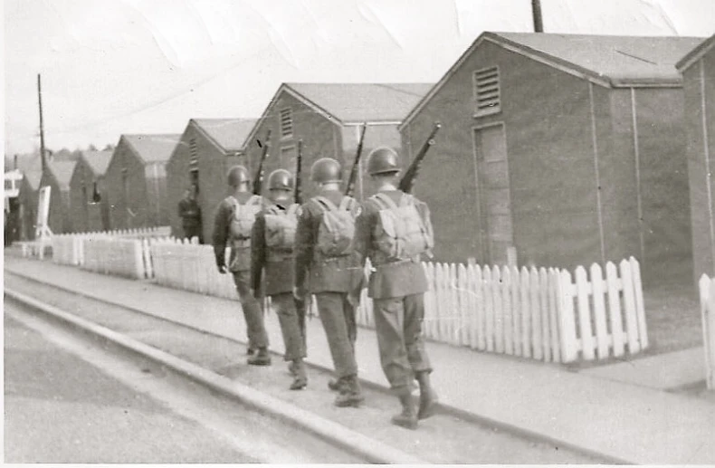 a group of men walking along side of a fence